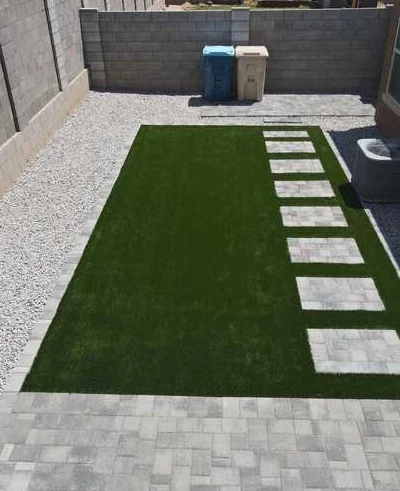 Rectangular turf lawn with a row of pale paver stepping stones and gravel edging.